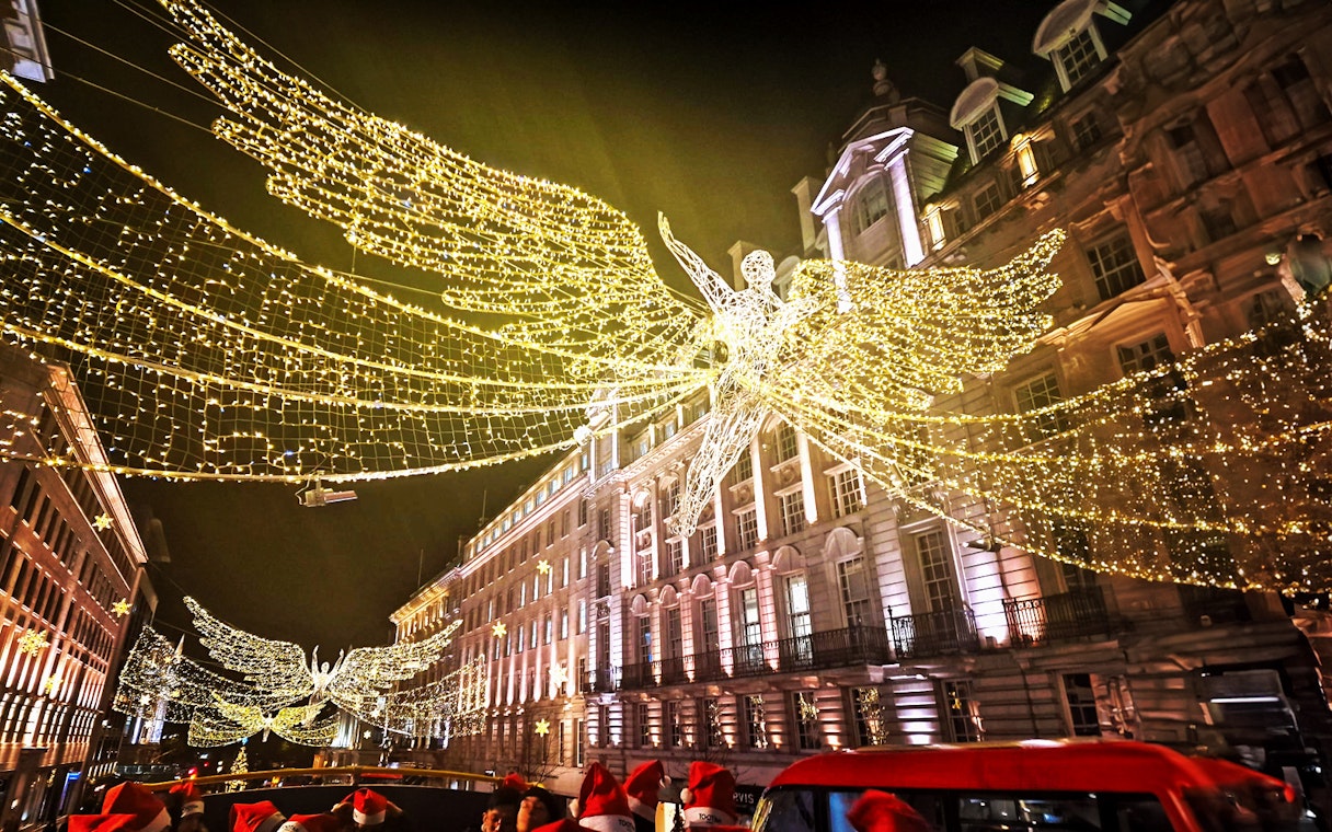 Double-decker bus under London Christmas lights on Tootbus route.
