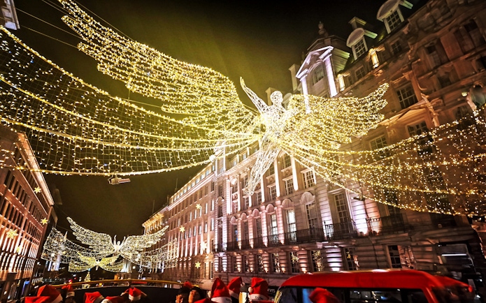 Double-decker bus under London Christmas lights on Tootbus route.