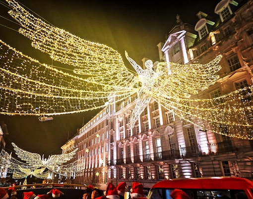 Double-decker bus under London Christmas lights on Tootbus route.