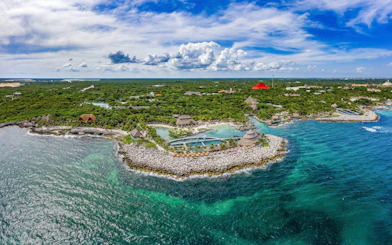 Aerial view of Xcaret Park's coastline with lush greenery and turquoise waters in Mexico.
