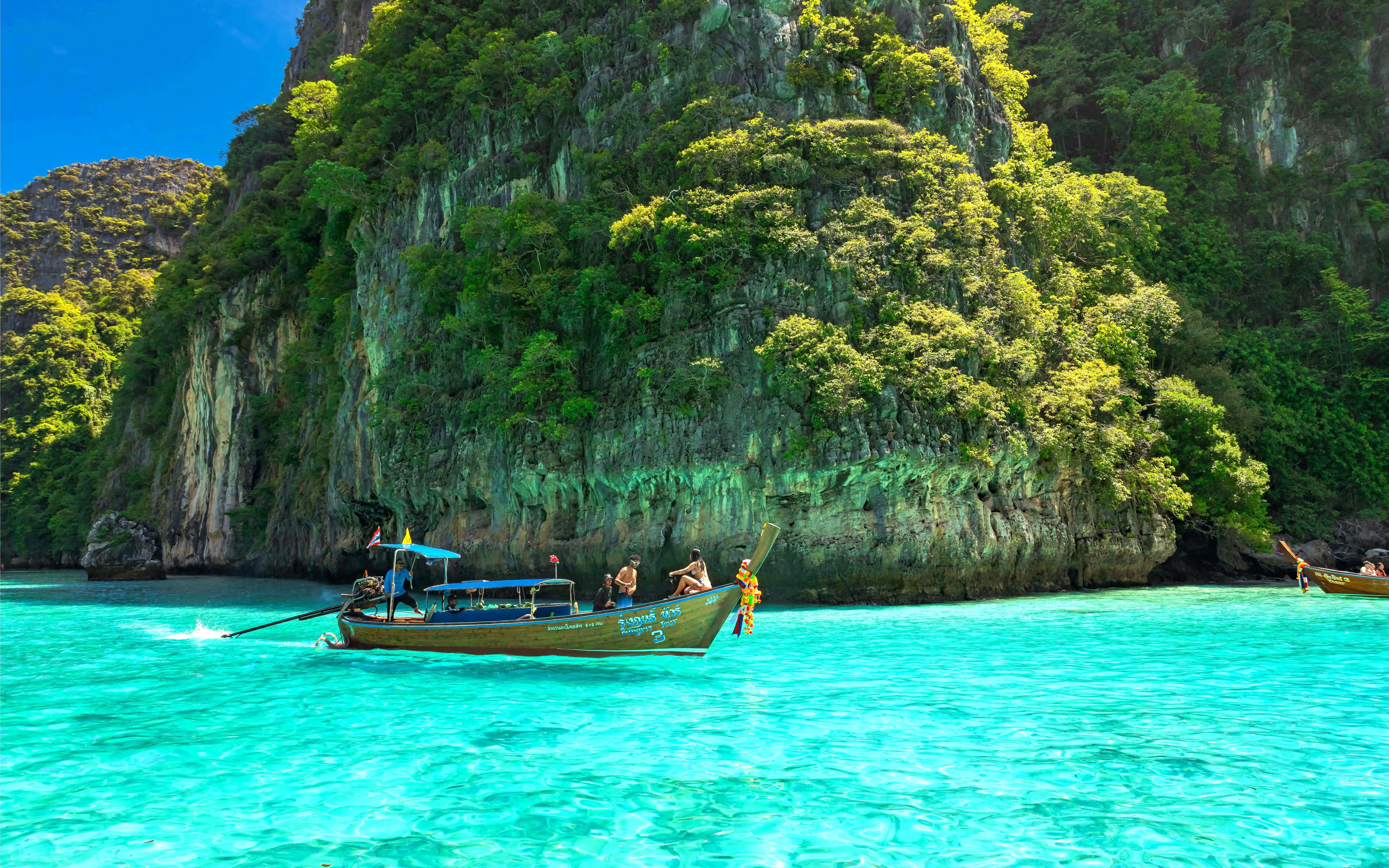 Speedboat near lush cliffs on Phi Phi Islands, Phuket tour.