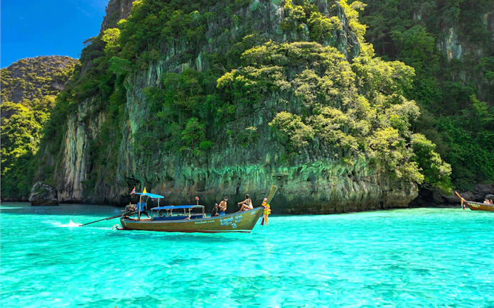 Speedboat near lush cliffs on Phi Phi Islands, Phuket tour.
