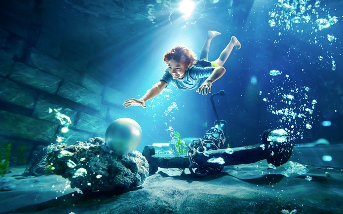 Young boy diving underwater for pearl at YAS Waterworld, Abu Dhabi.
