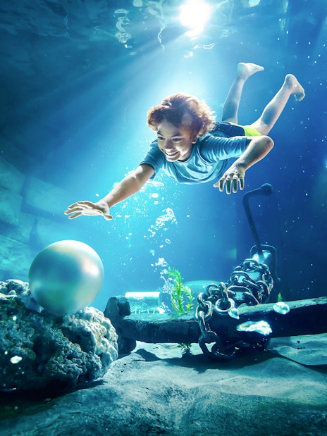 Young boy diving underwater for pearl at YAS Waterworld, Abu Dhabi.