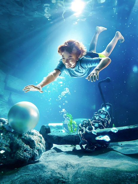 Young boy diving underwater for pearl at YAS Waterworld, Abu Dhabi.