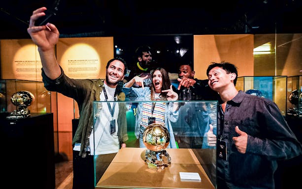 Visitors taking a selfie with the Ballon d'Or trophy at FC Barcelona Camp Nou Museum.