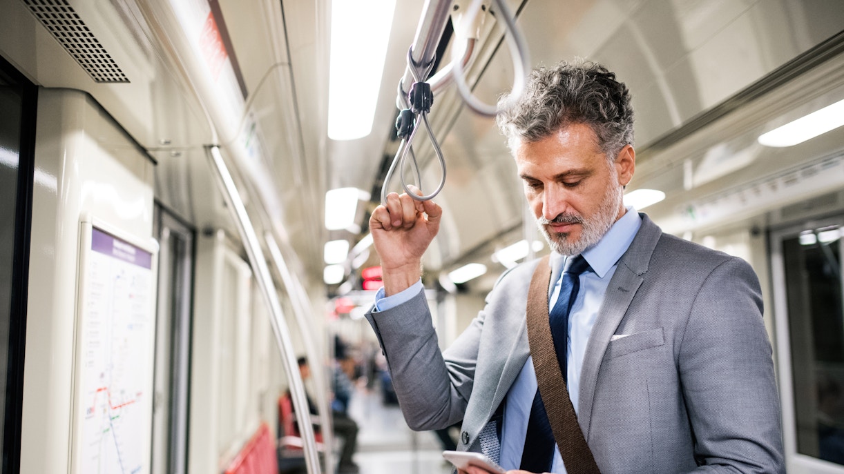 Man on metro heading to Gellert Baths, Budapest, checking phone.