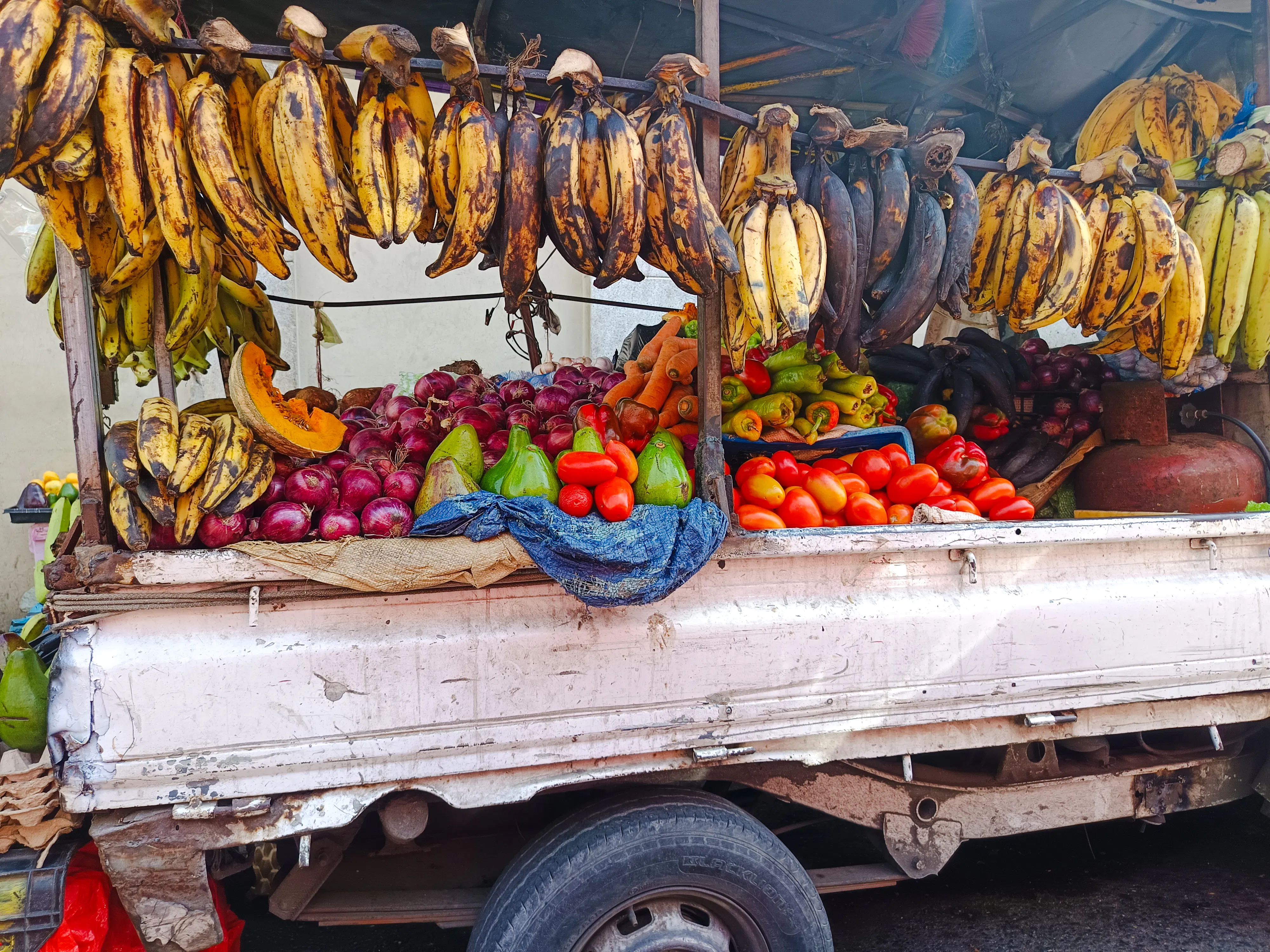 Fresh produce stall with bananas, onions, avocados, and peppers at Mercado Modelo, Santo Domingo.