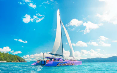 Sailing catamaran on clear waters during Airlie Beach Camira adventure.