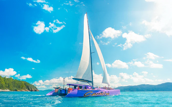 Sailing catamaran on clear waters during Airlie Beach Camira adventure.