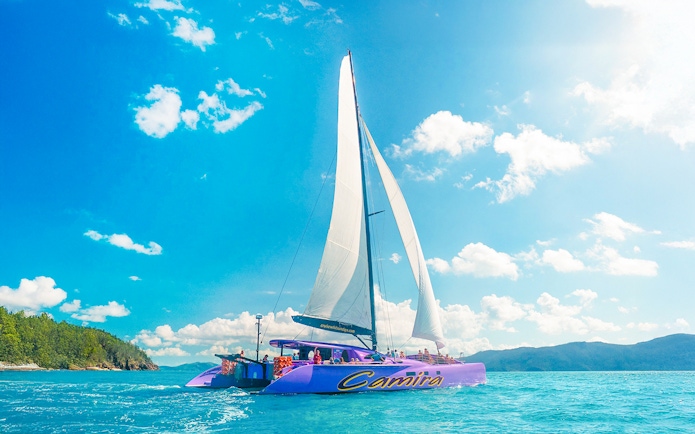 Sailing catamaran on clear waters during Airlie Beach Camira adventure.