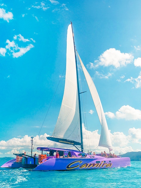 Sailing catamaran on clear waters during Airlie Beach Camira adventure.