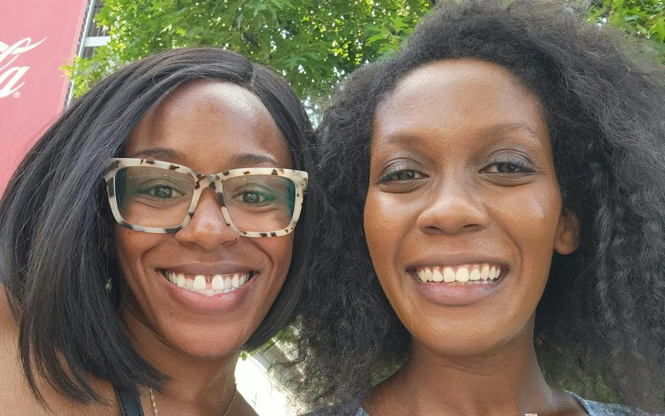 Two people smiling in front of a Coca-Cola sign during the Atlanta Downtown Highlights tour.