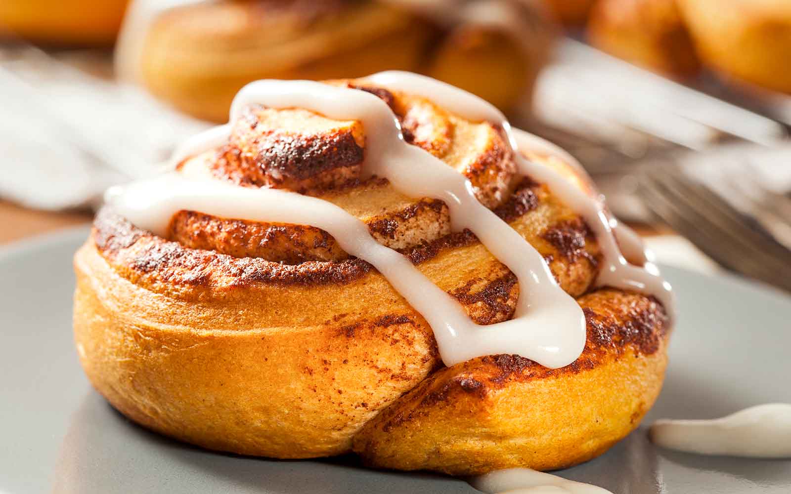 Homemade cinnamon bun with icing on a plate.