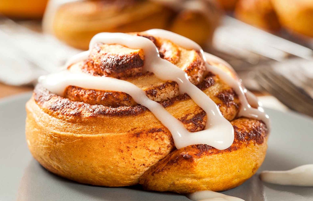 Homemade cinnamon bun with icing on a plate.