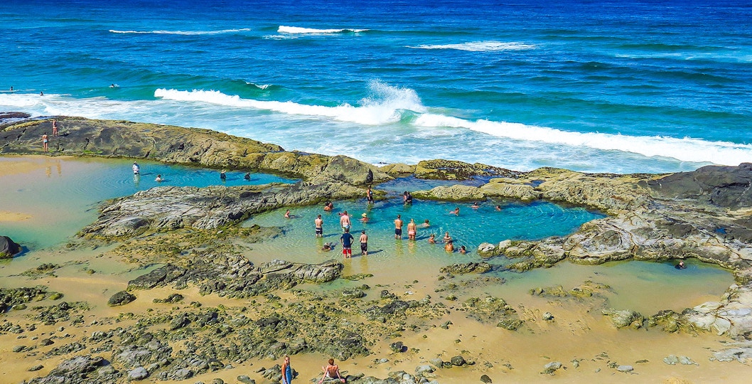Fraser Island beach with clear blue waters and lush greenery, K'gari, Australia.