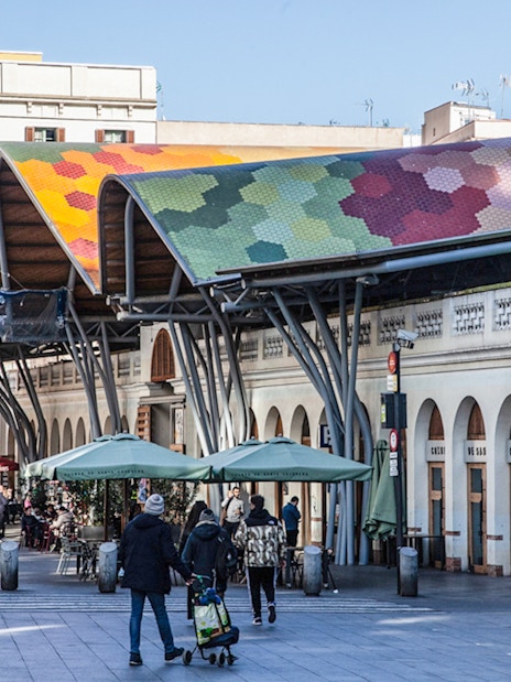 Colorful roof of Mercat de Santa Caterina in Barcelona with people walking nearby.