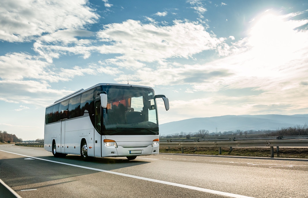 Tour bus traveling to Tenerife on a scenic highway under a bright sky.