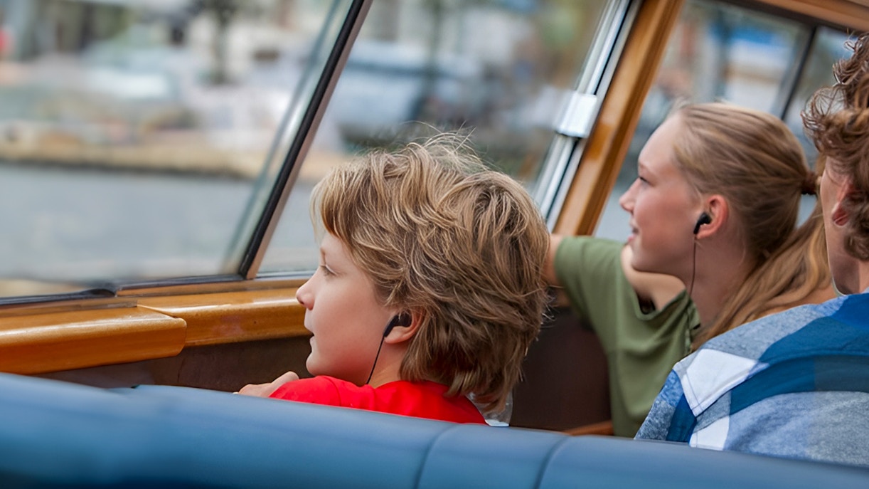 Passengers using audio guides on a canal cruise.