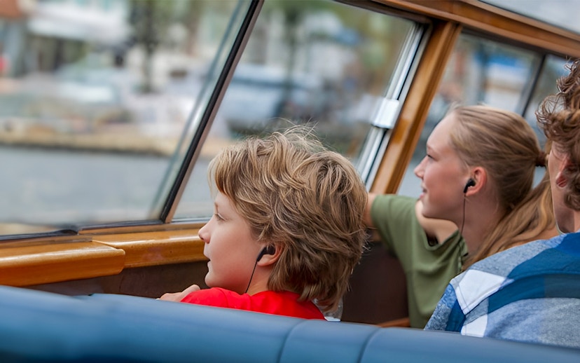 Passengers using audio guides on a canal cruise.