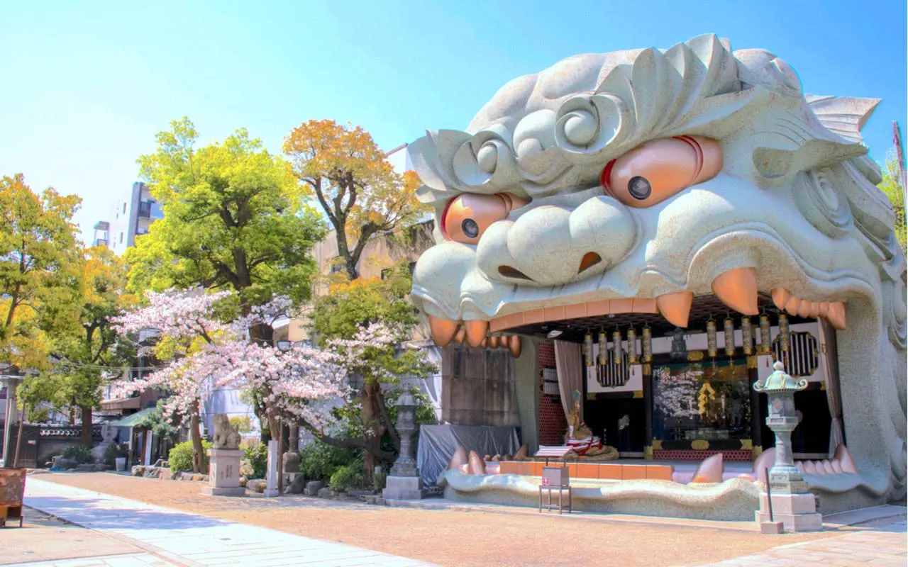 Lion-shaped entrance at Namba Yasaka Shrine in Osaka, surrounded by cherry blossoms.
