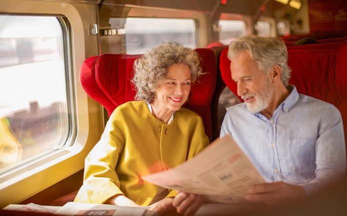 Couple enjoying Eurail Global Pass 1st class seats on a scenic train journey.