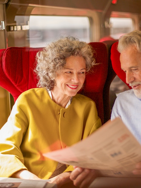 Couple enjoying Eurail Global Pass 1st class seats on a scenic train journey.