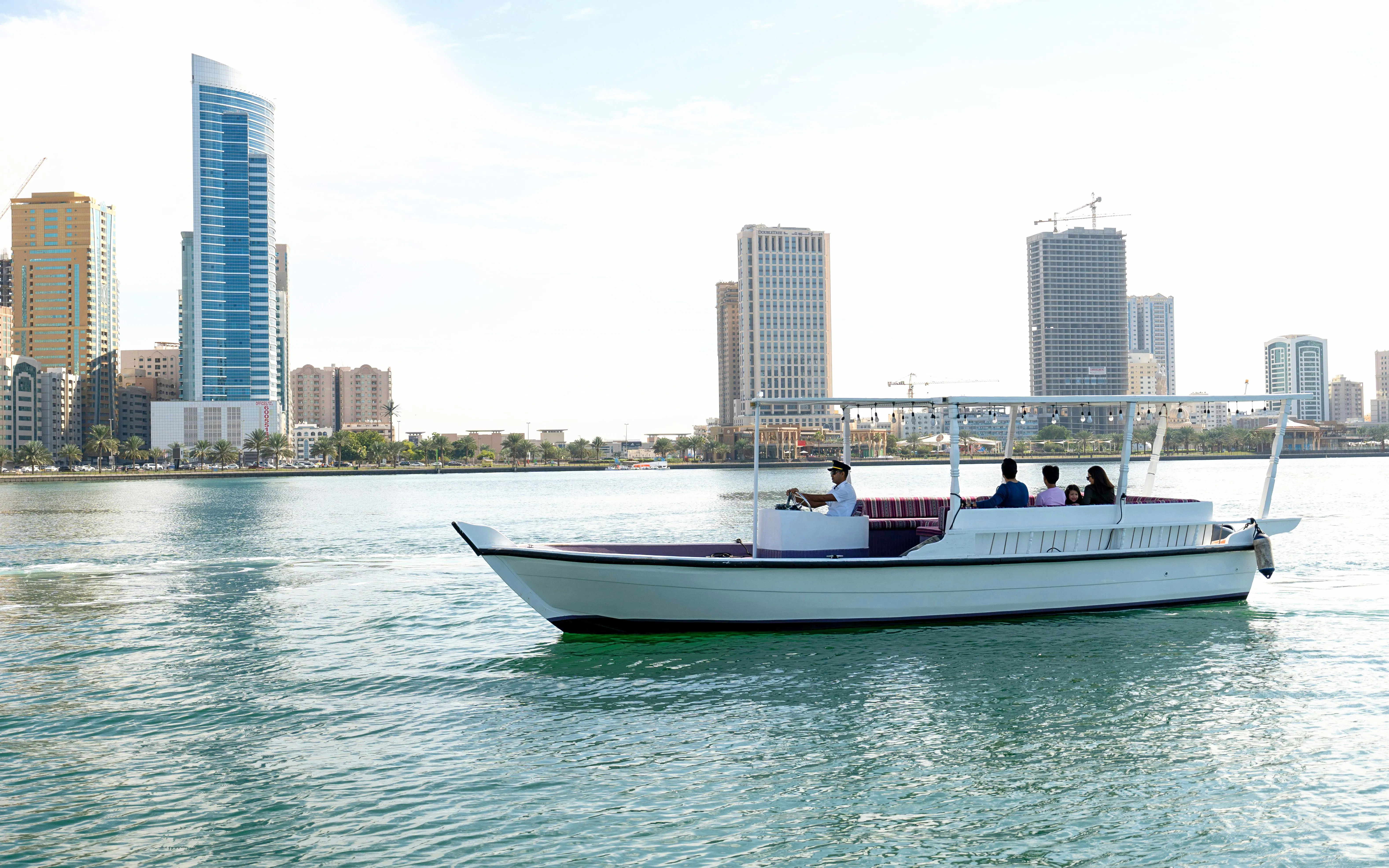 Boat tour on Khalid Lagoon with Sharjah skyline in the background.