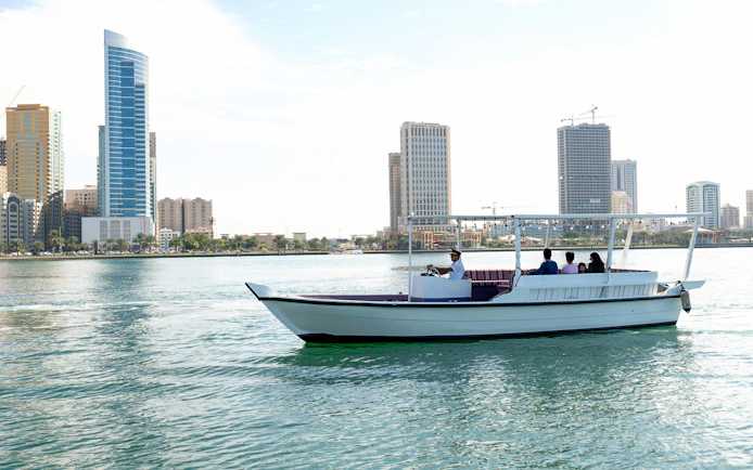Boat tour on Khalid Lagoon with Sharjah skyline in the background.