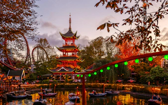 Tivoli Gardens pagoda with Halloween lights and boats on the lake in Copenhagen.