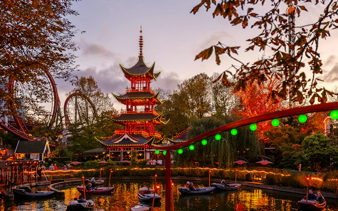 Tivoli Gardens pagoda with Halloween lights and boats on the lake in Copenhagen.