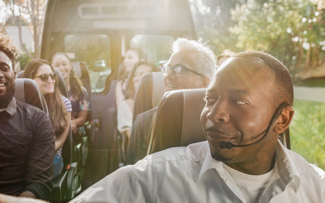 Tour guide leading a group on a Celebrity Homes Tour bus.