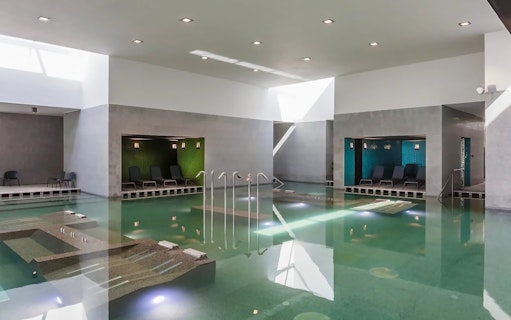 Indoor pool at Pesterzsebet Bath, Budapest with lounge chairs and modern design.