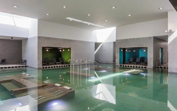 Indoor pool at Pesterzsebet Bath, Budapest with lounge chairs and modern design.