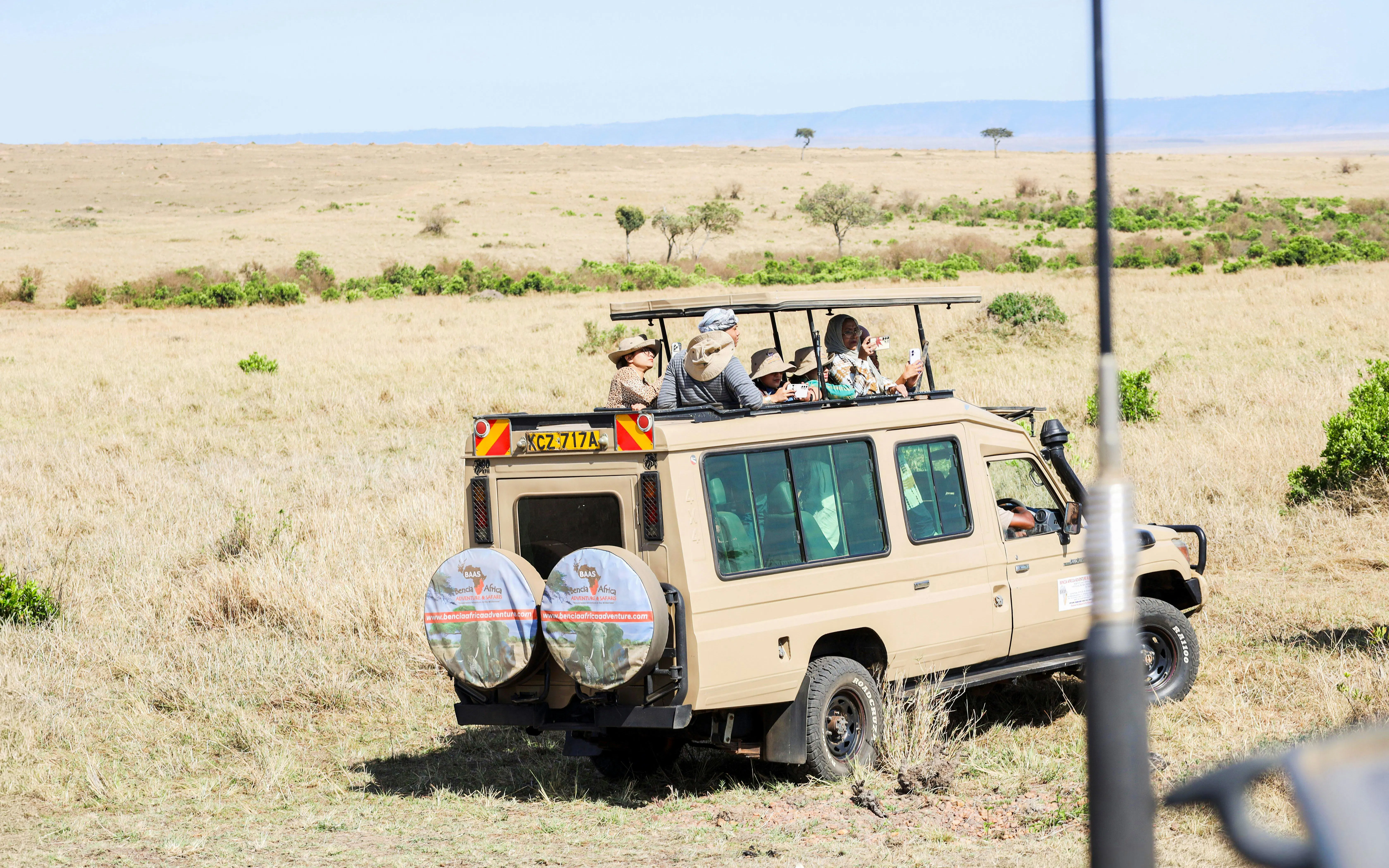 Safari vehicle with tourists in Masai Mara savannah, Kenya.