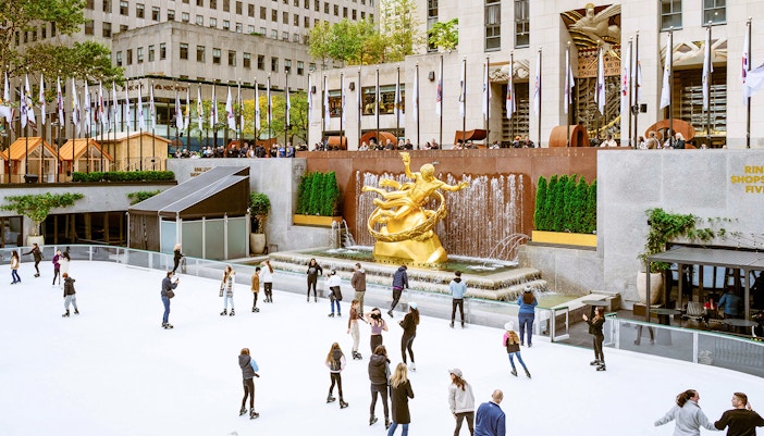 Ice skaters at Rockefeller Center with Prometheus statue in New York City.