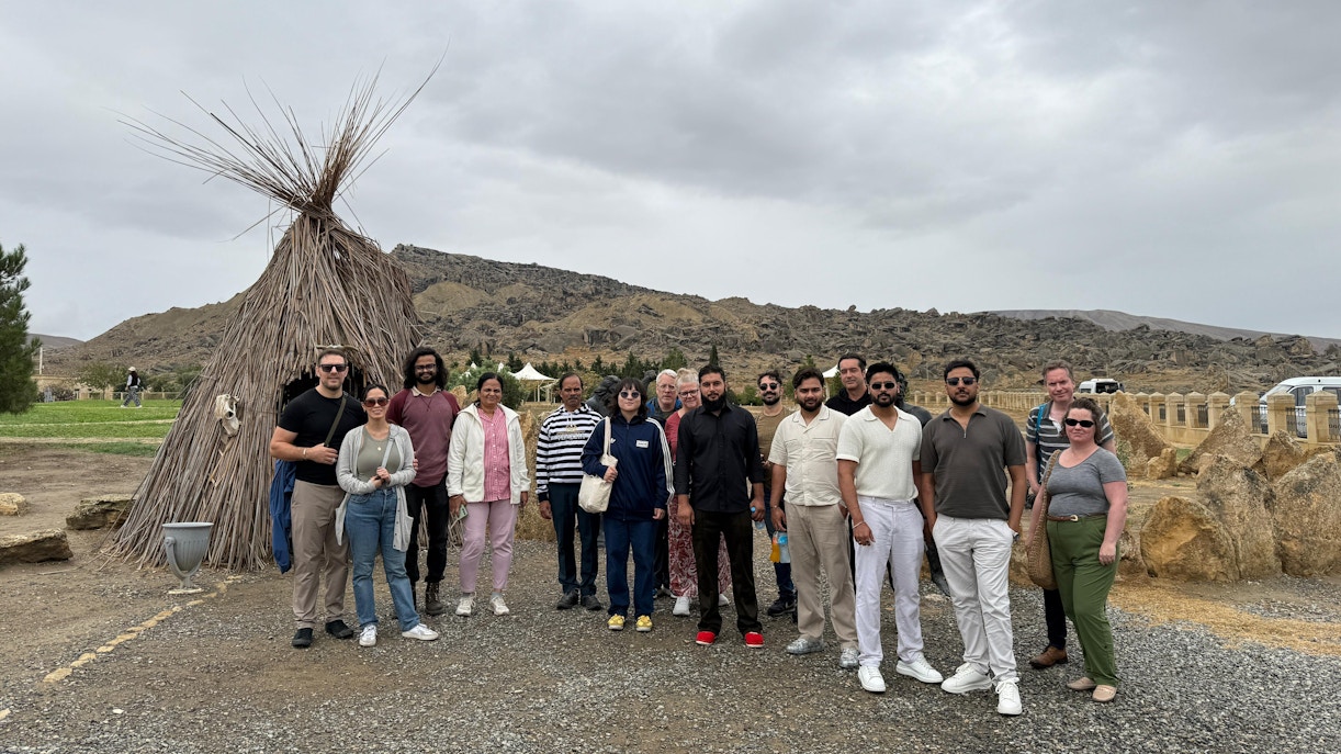 Group of tourists at Gobustan National Park with mud volcanoes in the background.
