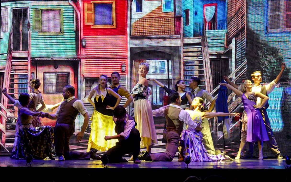 Dancers performing at Madero Tango Show with colorful La Boca backdrop.