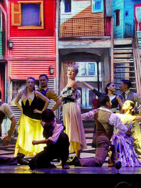 Dancers performing at Madero Tango Show with colorful La Boca backdrop.