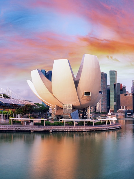 ArtScience Museum in Singapore with city skyline at sunset.