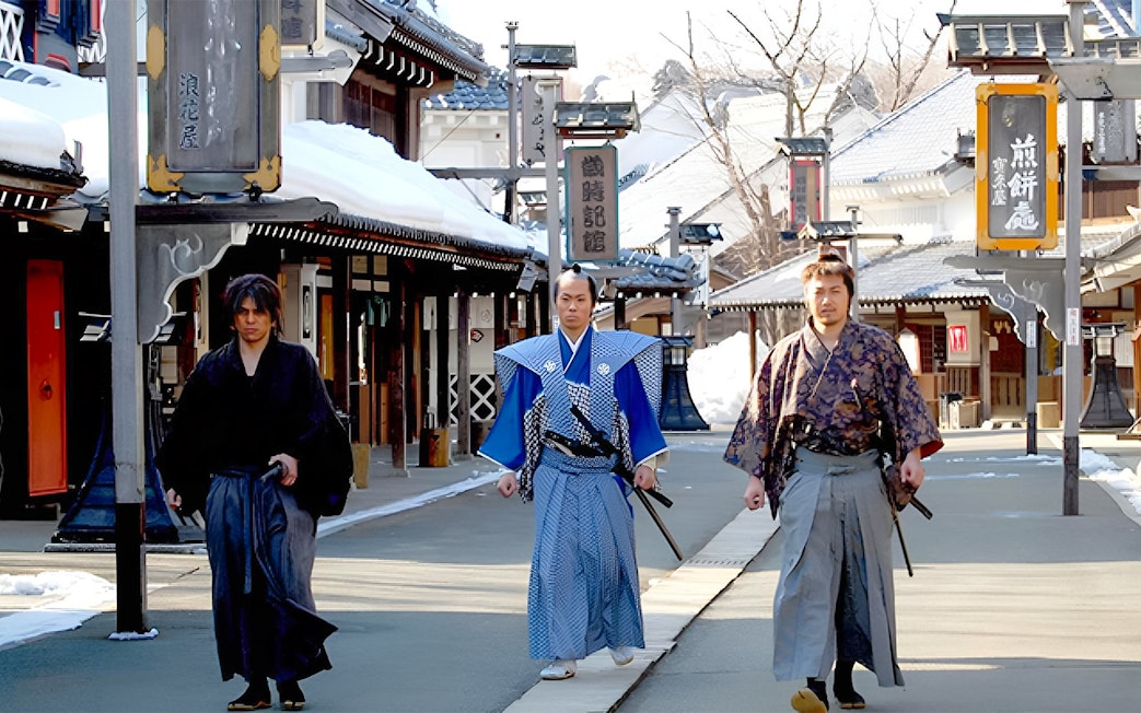 Samurai actors walking in traditional attire at Noboribetsu Date Jidaimura, Japan.
