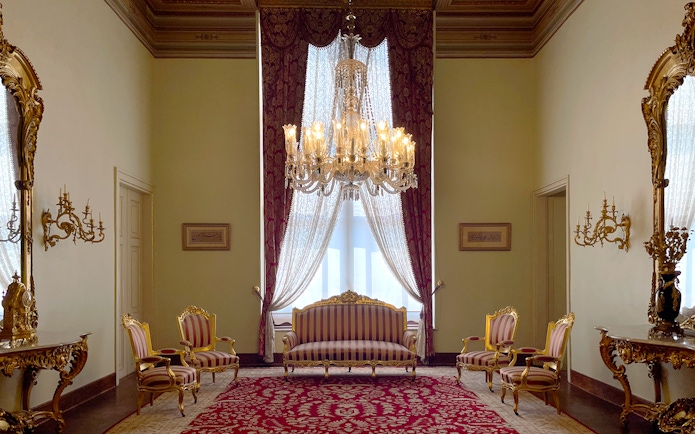 Interior of Dolmabahçe Palace with chandelier, ornate furniture, and red carpet in Istanbul, Turkey.