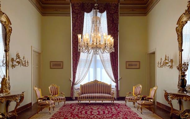 Interior of Dolmabahçe Palace with chandelier, ornate furniture, and red carpet in Istanbul, Turkey.