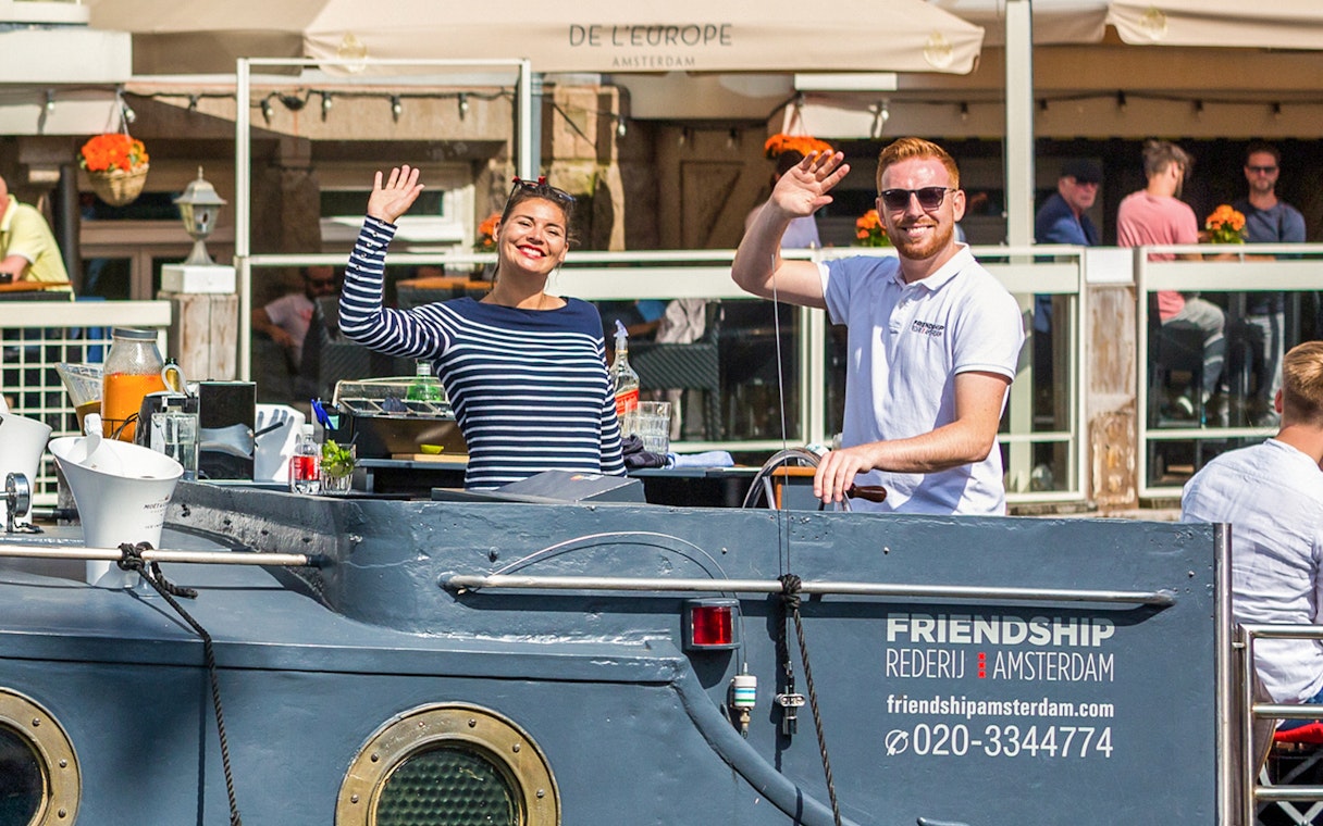 People waving on a canal cruise boat in Amsterdam.