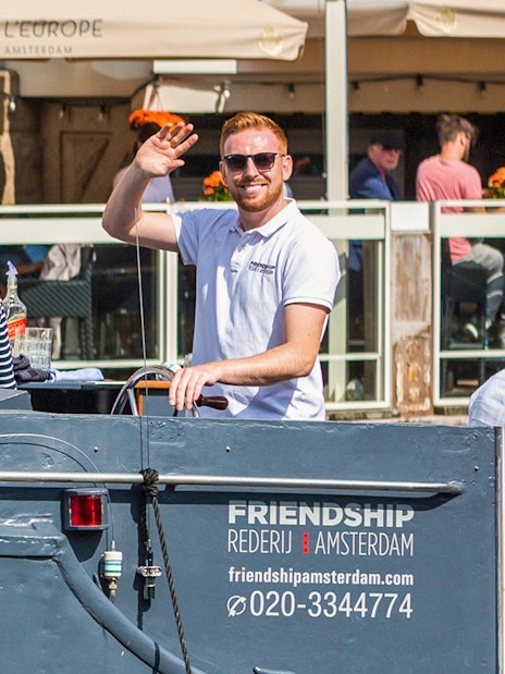 People waving on a canal cruise boat in Amsterdam.