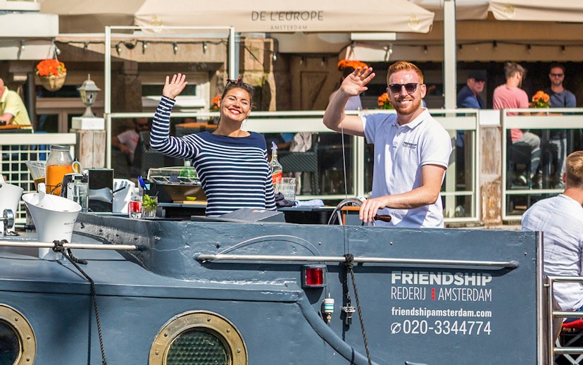 People waving on a canal cruise boat in Amsterdam.