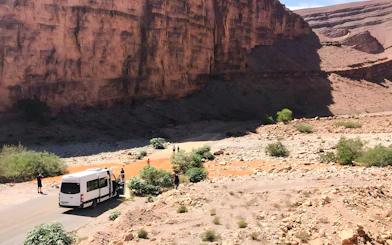 Van traveling through rocky terrain in Agafay Desert, Marrakech, with desert mountains in the background.