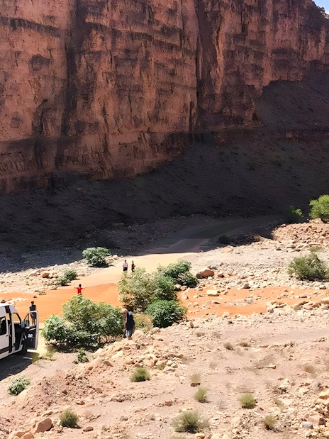 Van traveling through rocky terrain in Agafay Desert, Marrakech, with desert mountains in the background.