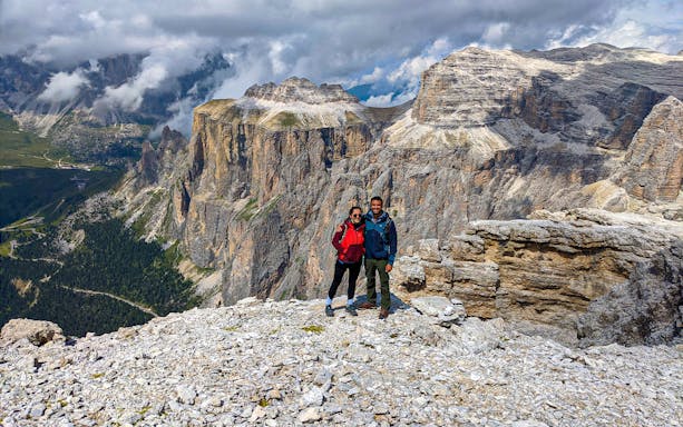 Couple standing on rocky terrain with Dolomites mountains in the background, Italy.