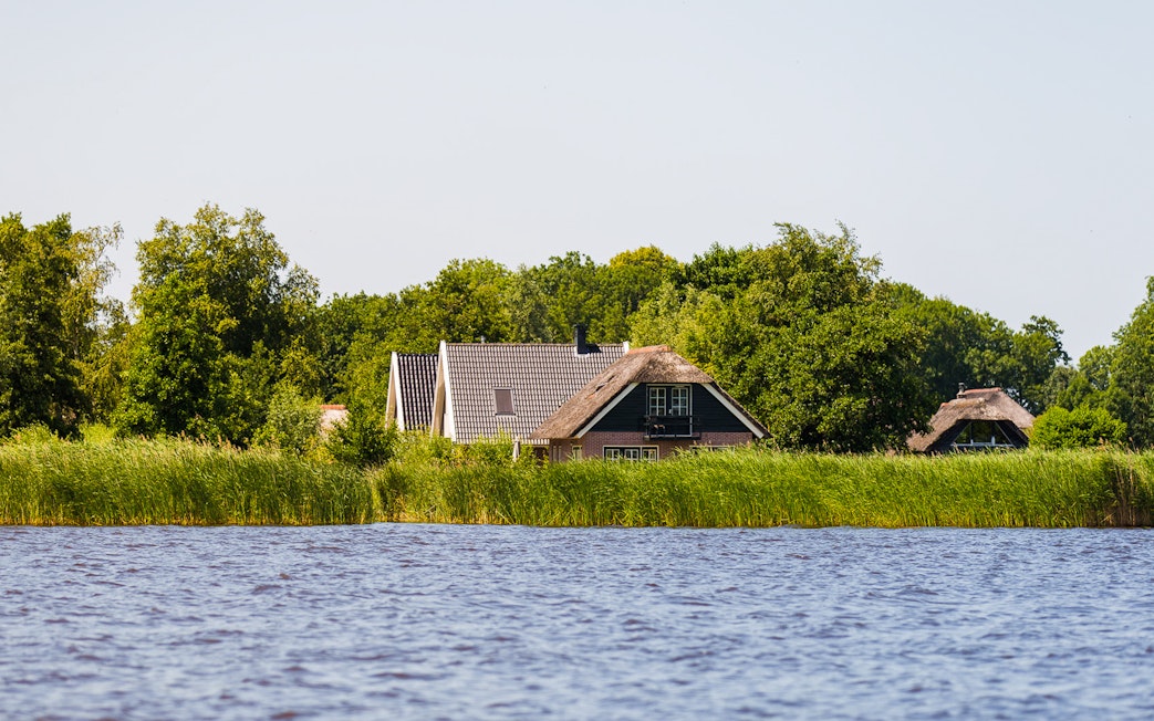 Traditional houses by the water in Giethoorn, surrounded by greenery, seen on a day trip from Amsterdam.